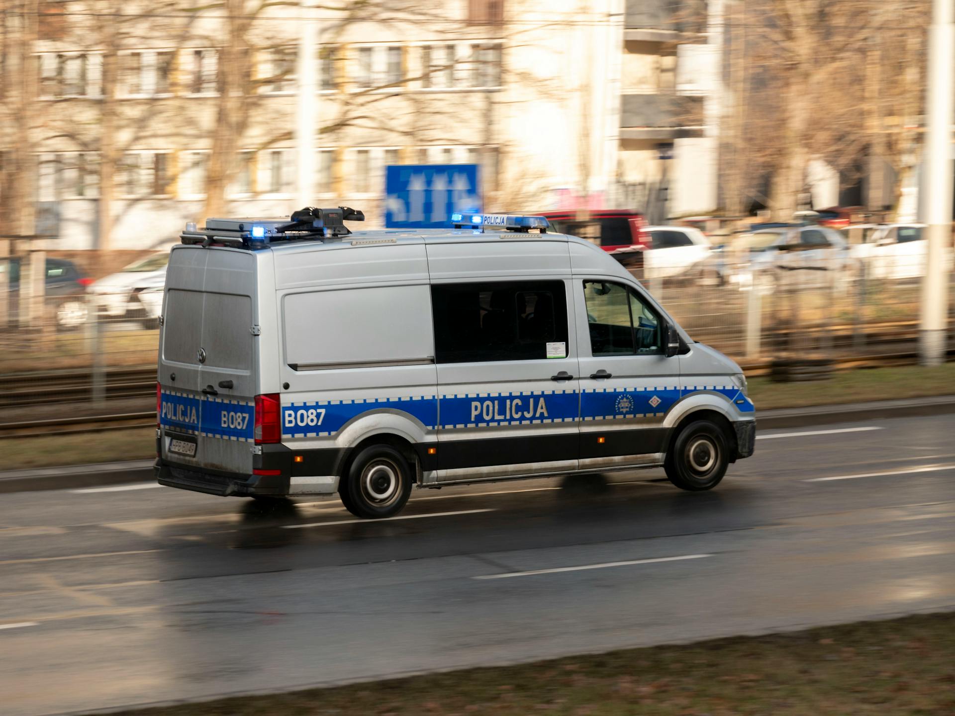 Policyjny radiowóz w kolorach niebiesko-białych z napisem POLICJA zaparkowany na ulicy w Polsce