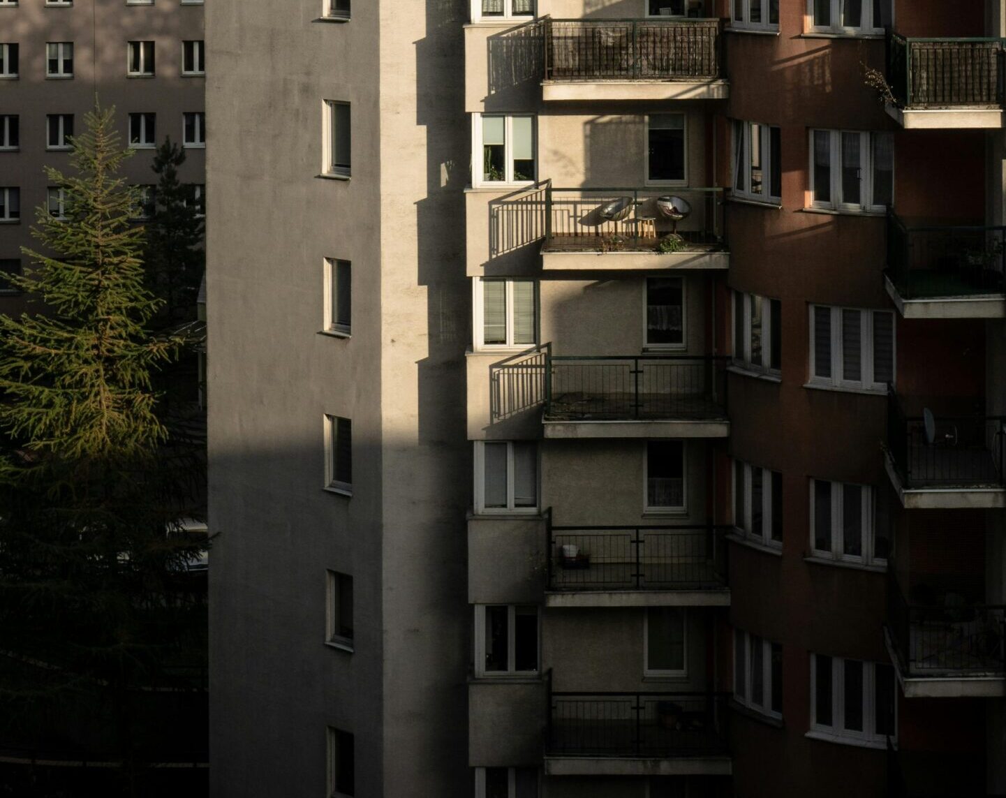 Blok mieszkalny o zachodzie słońca na tle ciemnych burzowych chmur, betonowa architektura osiedla